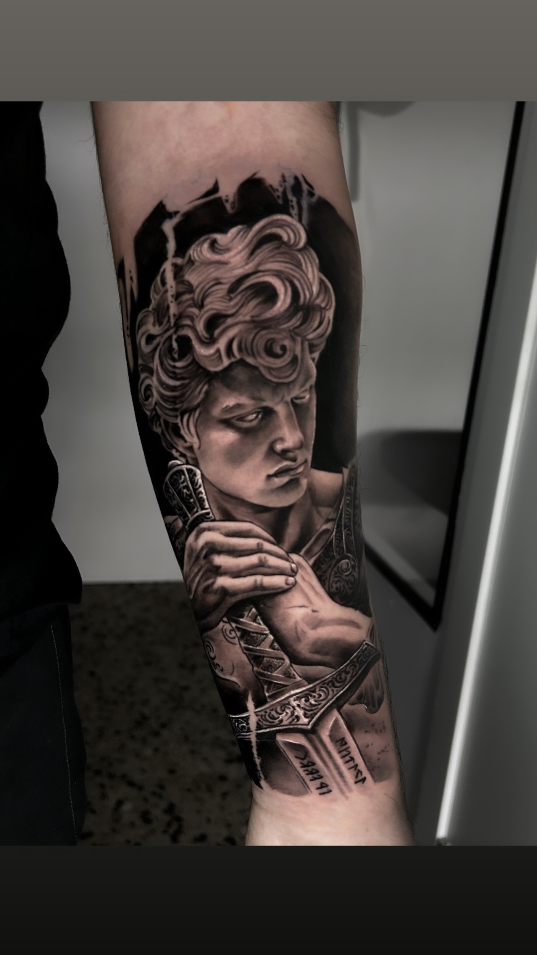 David con espada, realismo escultórico en antebrazo